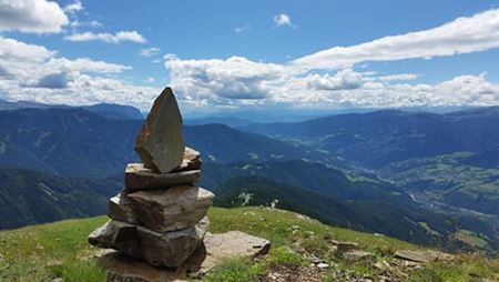 stack of rocks sculpture on a hill overlooking a wide mountain landscape