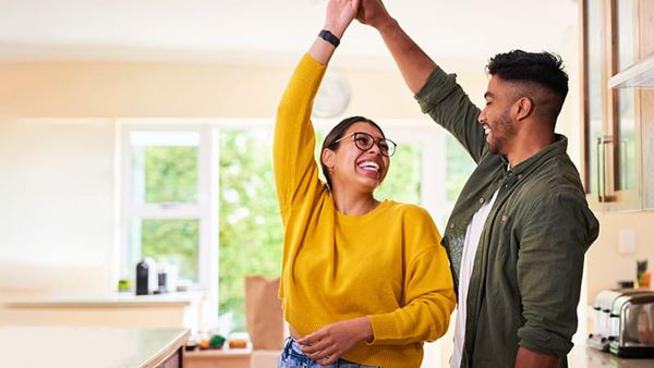 A young couple dancing together in their kitchen A young couple dancing together in their kitchen